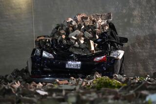 A car crushed by falling bricks from a fallen building wall sits in a downtown parking lot after a severe thunderstorm passed through, Thursday, May 16, 2024, in Houston. (AP Photo/David J. Phillip)