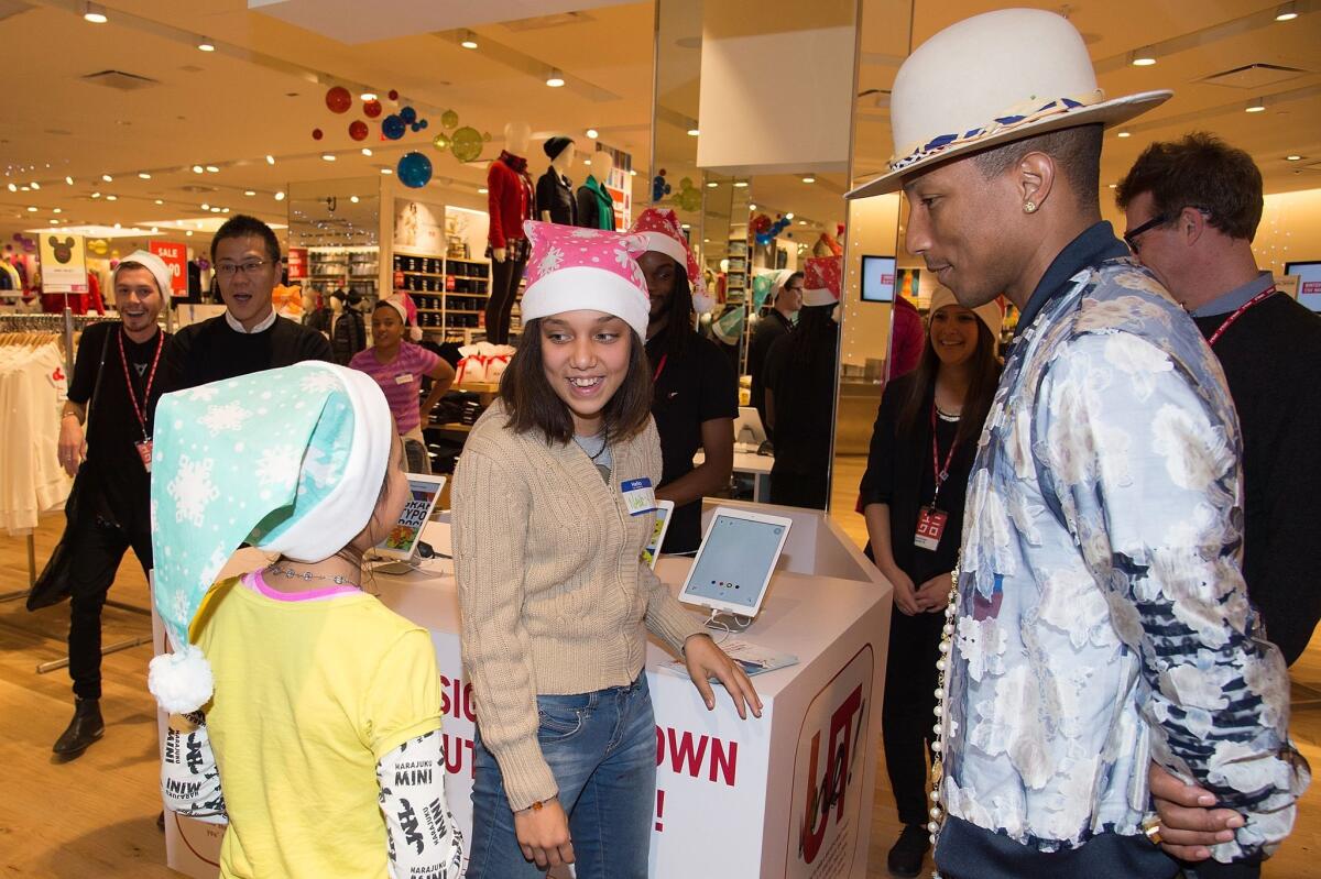 Pharrell Williams talks with kids at Uniqlo's holiday shopping party at the Beverly Center store on Tuesday.