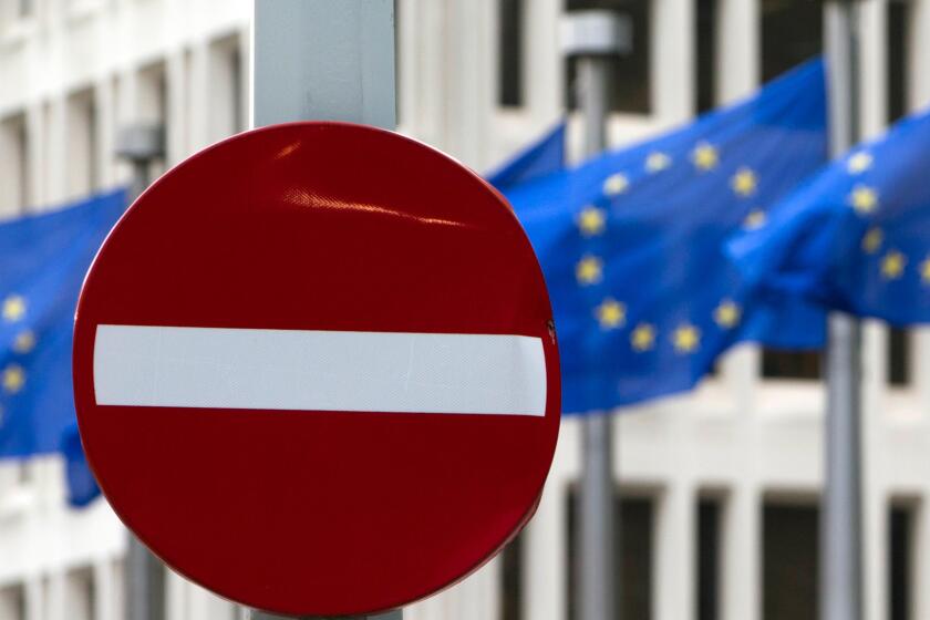 EU flags flutter in the wind behind a no-entry street sign in front of EU headquarters in Brussels on Friday, June 24.