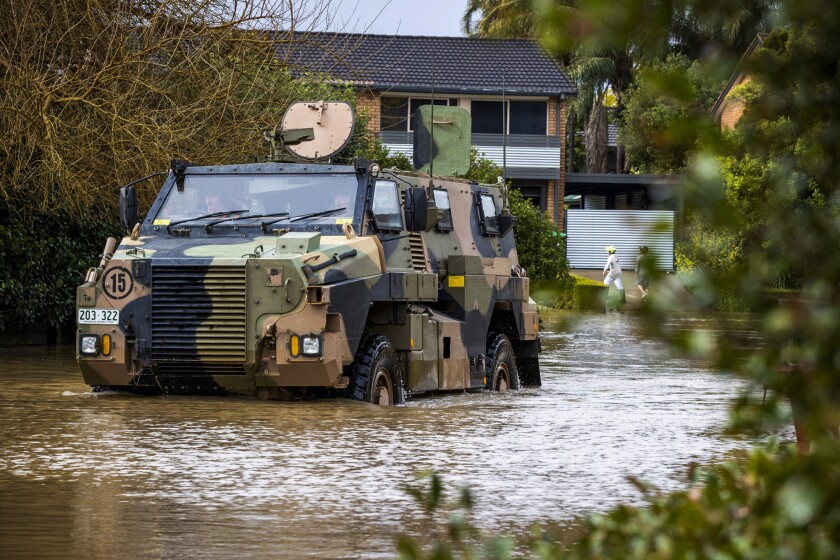 An Australian Army Bushmaster Protected Mobility Vehicle drives through a flooded street in McGrath Hills on the outskirts of Sydney, Monday, July 4, 2022. More than 50,000 residents of Sydney and its surrounds have been told to evacuate or prepare to abandon their homes on Tuesday as Australia's largest city braces for what could be its worst flooding in 18 months. (CPL David Cotton/Australian Defense Dept. via AP)