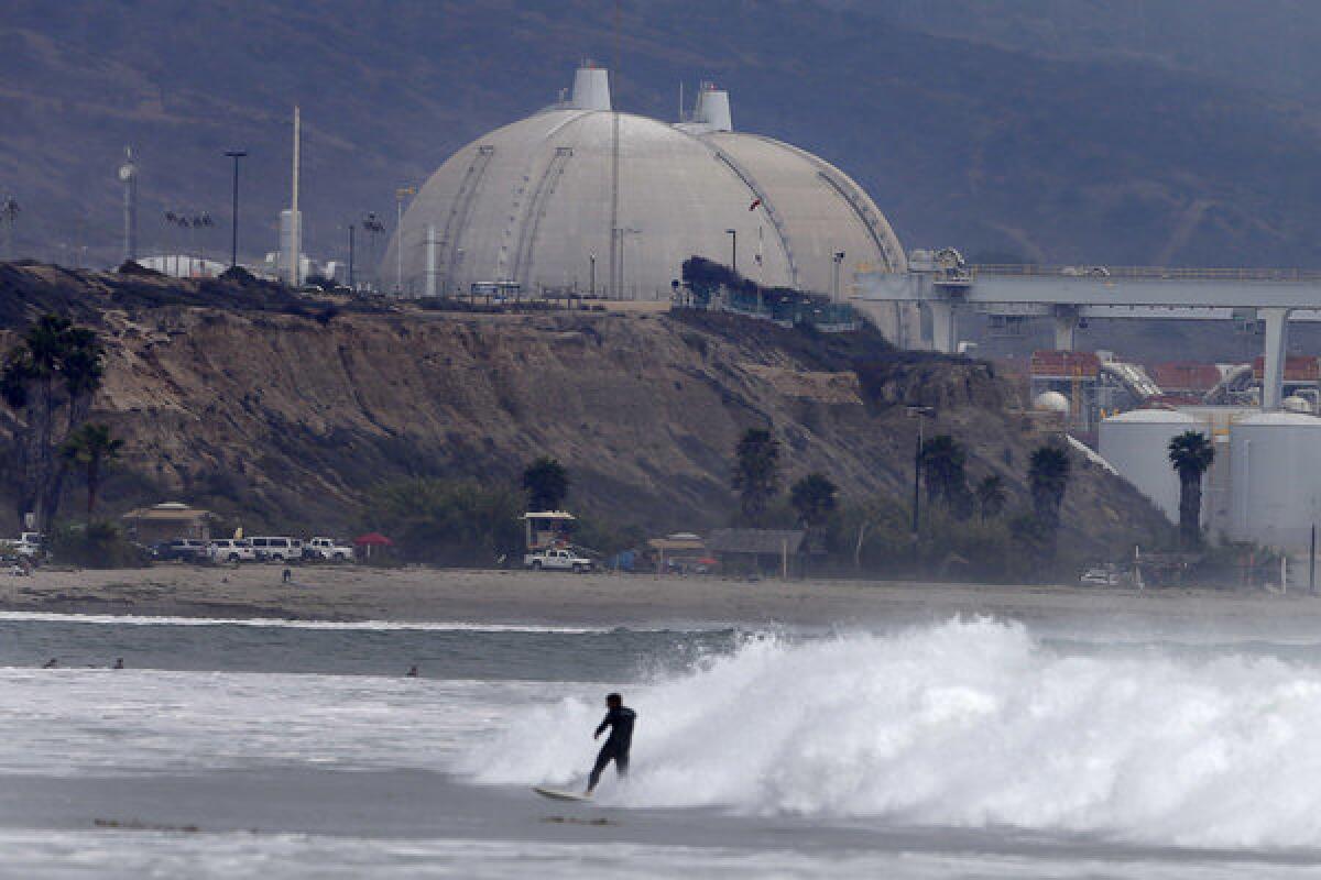 Although it's been decided to decommission the San Onofre nuclear power plant, California's Public Utilities Commission still has to decide who should pay for its early retirement. Above: A surfer rides a wave in front of San Onofre.