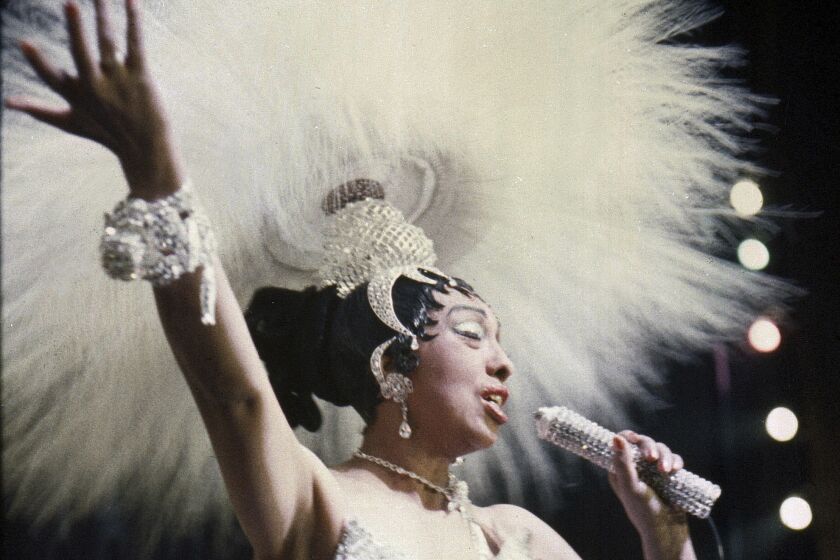 FILE - In this file photo dated May 27, 1957, Entertainer Josephine Baker holds a rhinestone-studded microphone as she performs during her show "Paris, mes Amours" at the Olympia Music Hall in Paris, France. The remains of American-born singer and dancer Josephine Baker will be reinterred at the Pantheon monument in Paris, Le Parisien newspaper reported Sunday Aug. 22, 2021, that French President Emmanuel Macron has decided to bestow the honor. Josephine Baker is a World War II hero in France and will be the first Black woman to get the country’s highest honor. (AP Photo/File)