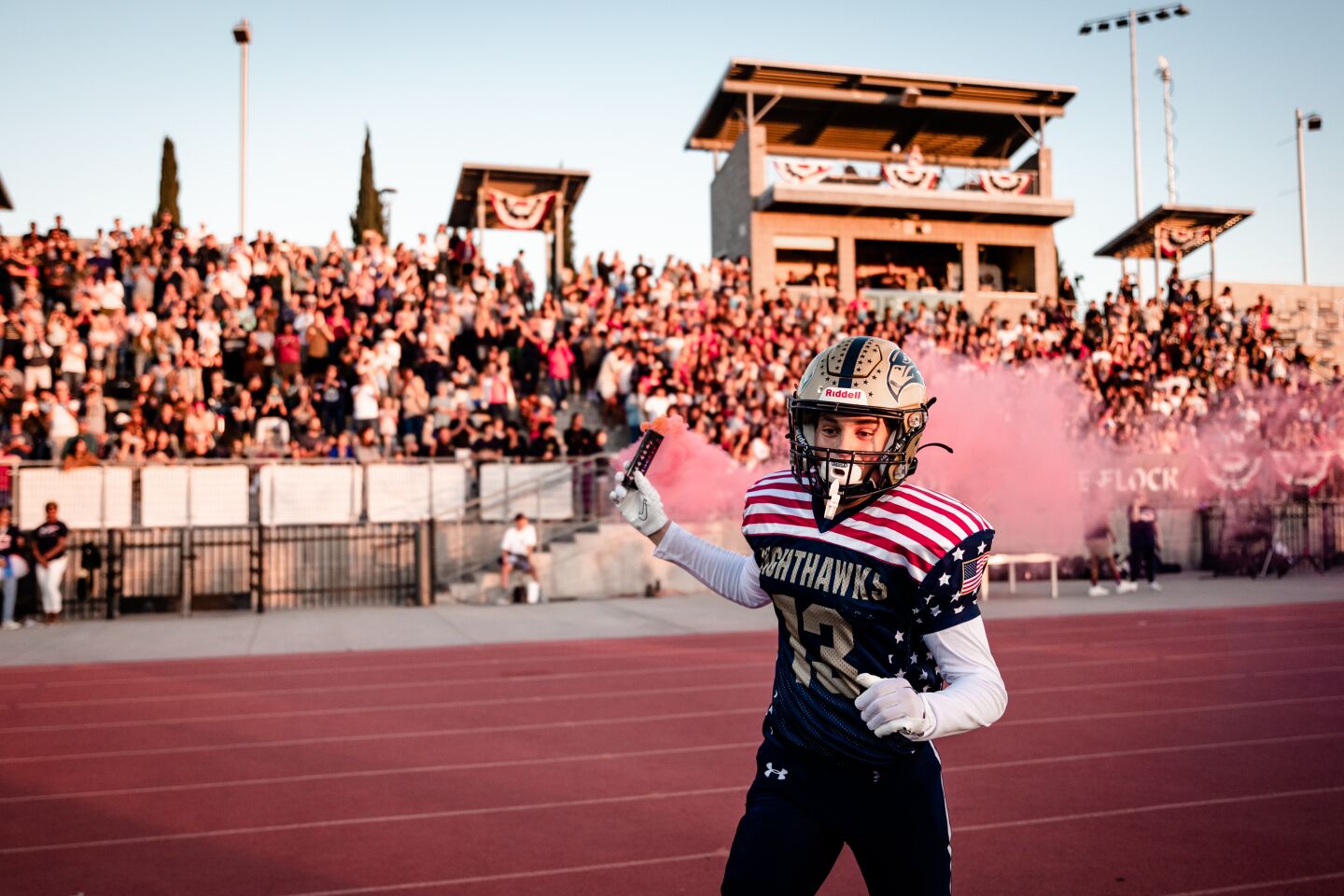 Del Norte football player Kyle Stephenson runs out with a red smoke grenade at the Military Appreciation Night.