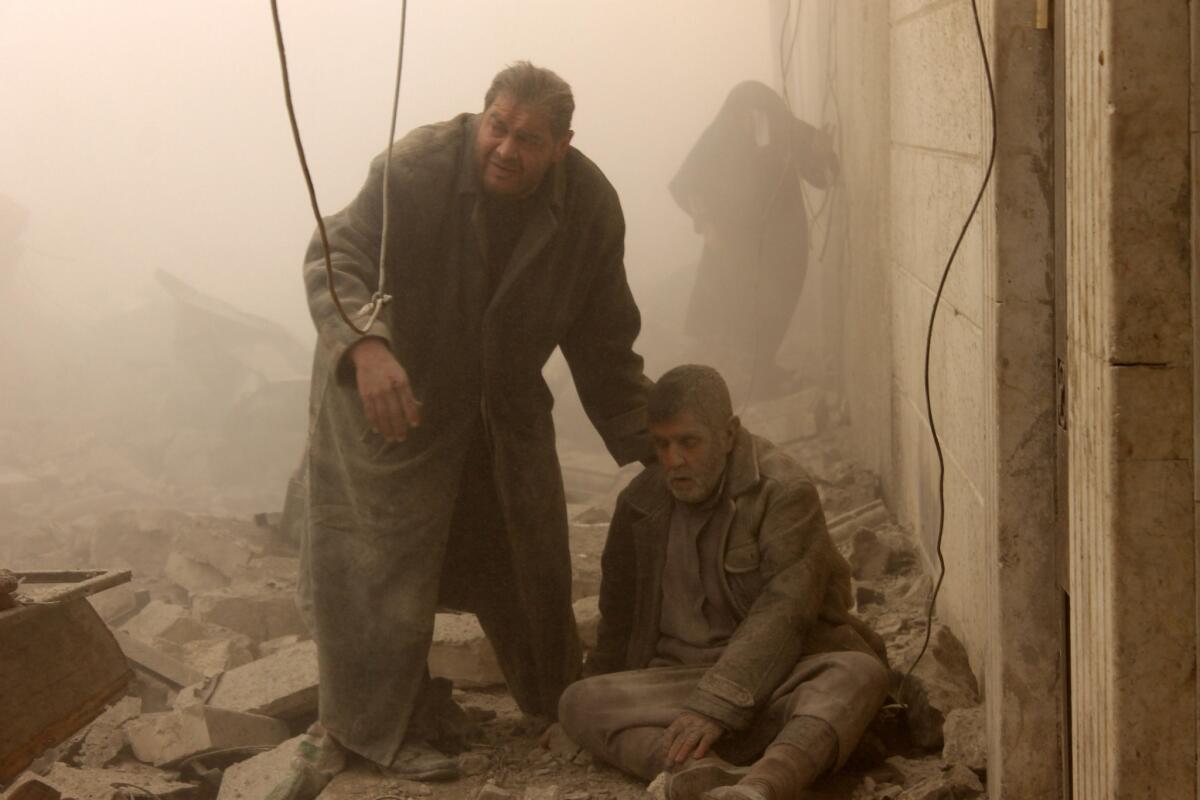 A Syrian man helps an injured man following an airstrike in Aleppo's Maadi neighborhood on Tuesday.