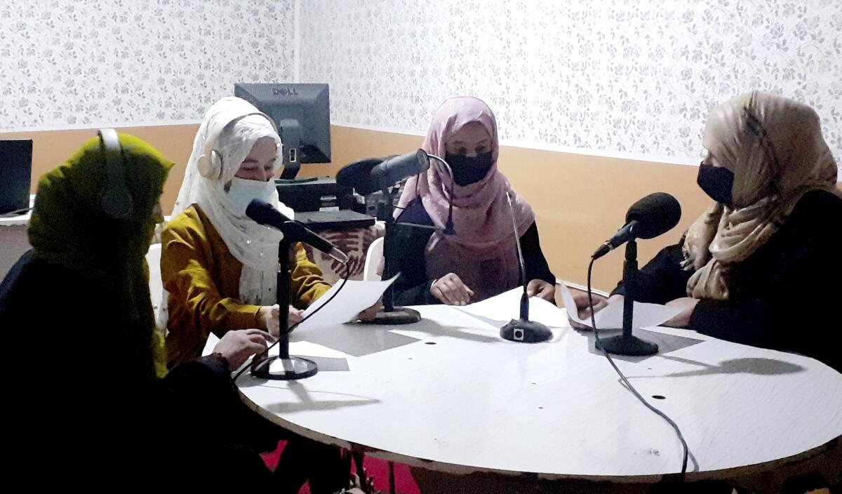 Afghan women at a table of microphones at a radio station