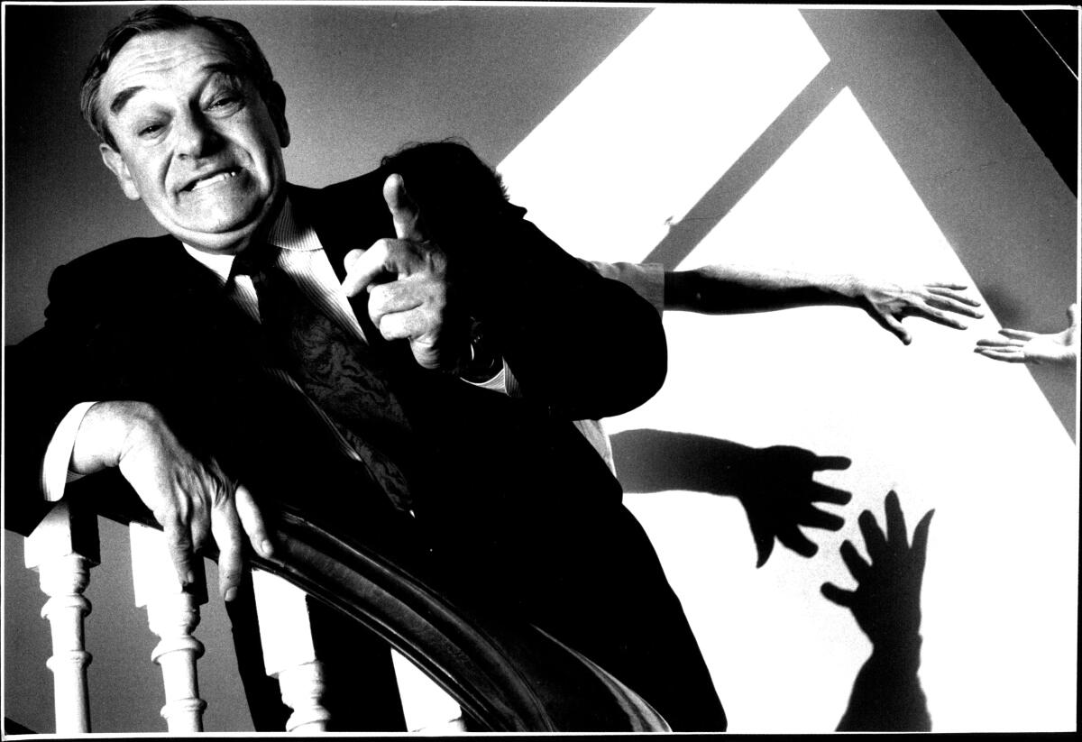 Herb Cohen standing on a staircase and pointing at the camera