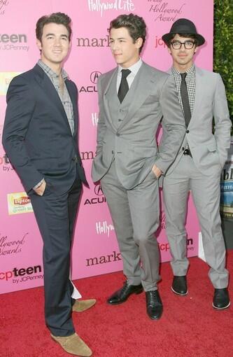 The Jonas Brothers stick together as Kevin, left, and Joe, right, support their brother Nick, who won artist of the year.