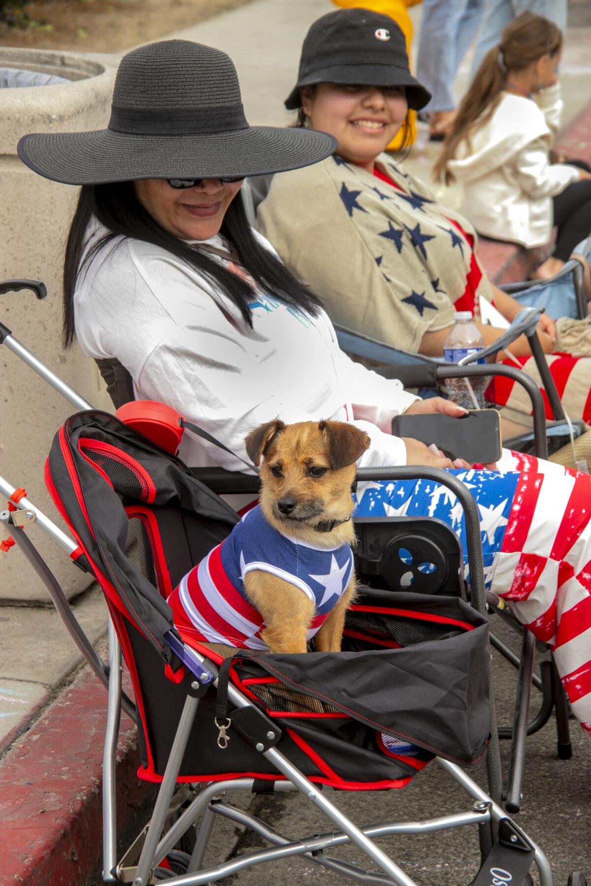 Draco the patriotic dog, pictured with Jayoli Sebellon and Thania Delgado, waits on Pacific Coast Highway for the parade.