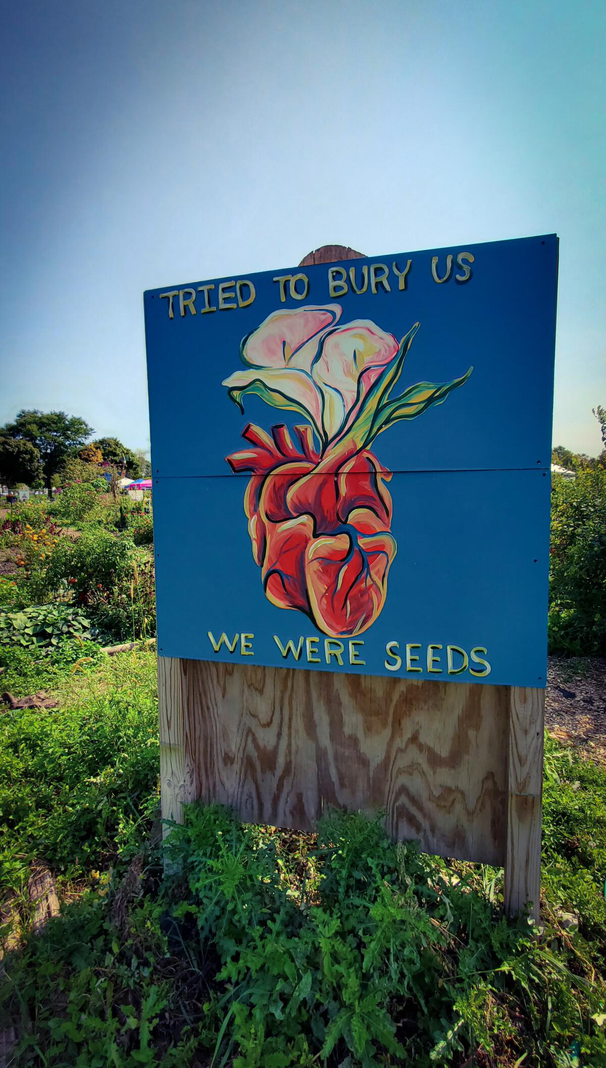 A painting in Alice's Garden with the words "Tried to bury us. We were seeds."