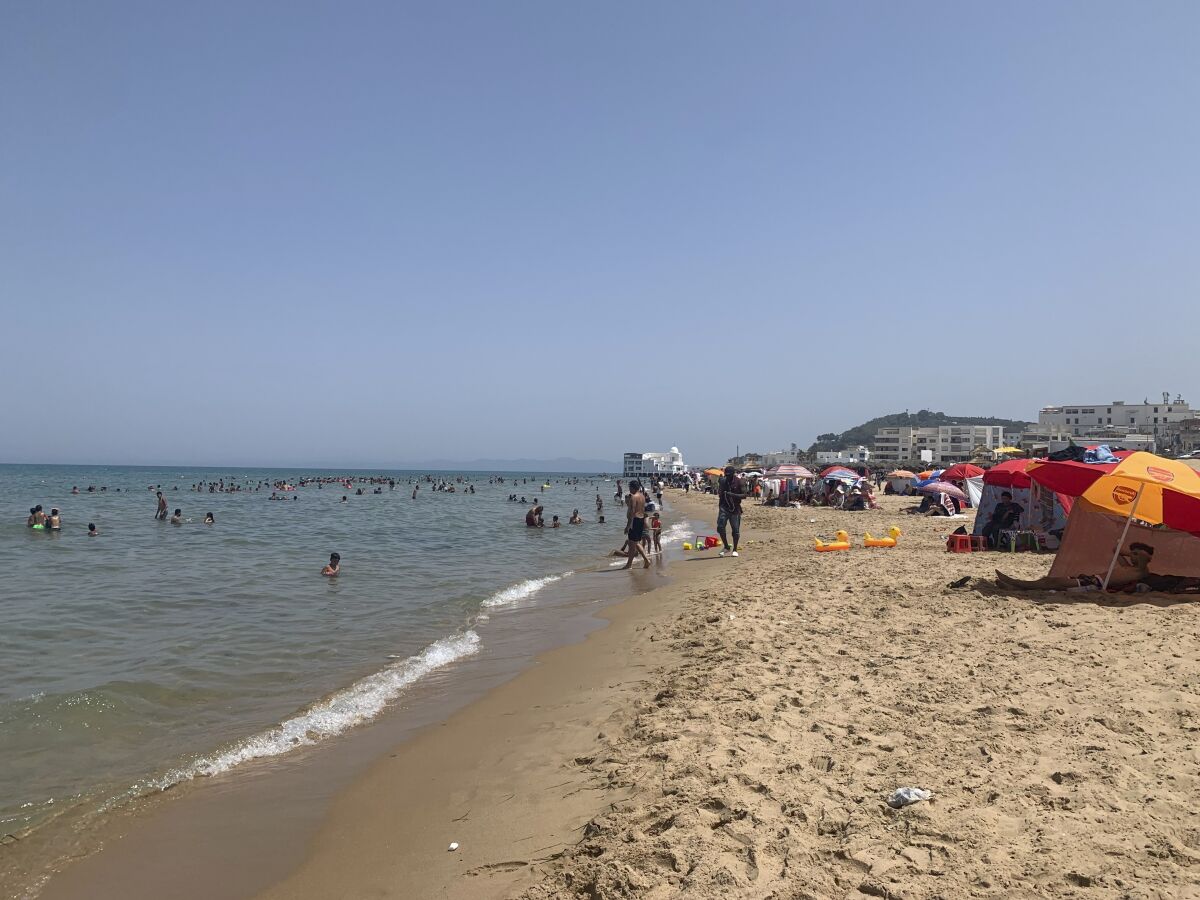 Tunisians relax on La Marsa beach outside Tunis, Sunday, Aug. 1, 2021, as the country remained in limbo more than a week after President Kais Saied fired the prime minister, froze the parliament and took on executive powers. (AP Photo/Francesca Ebel)