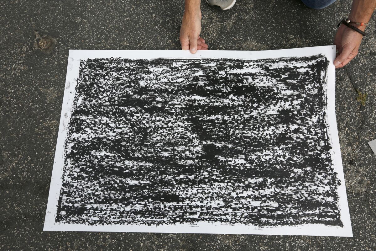 Artist Jeff Beall displays one of the rubbings taken at the site of an unsolved death related to the 1992 L.A. riots — in this case that of a 23-year-old Latino man named Arturo C. Miranda. (Mark Boster / Los Angeles Times)