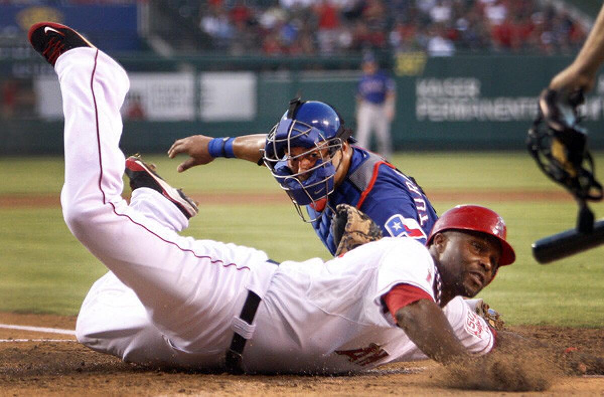Torii Hunter scores a run for the Angels by reaching around the tag of catcher Yorvit Torrealba in a game against the Rangers in 2011.