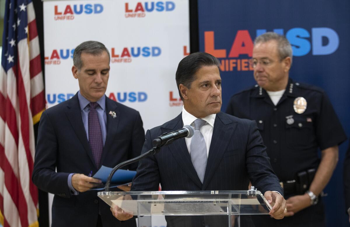 The Los Angeles mayor, left, school superintendent and police chief stand before a podium.