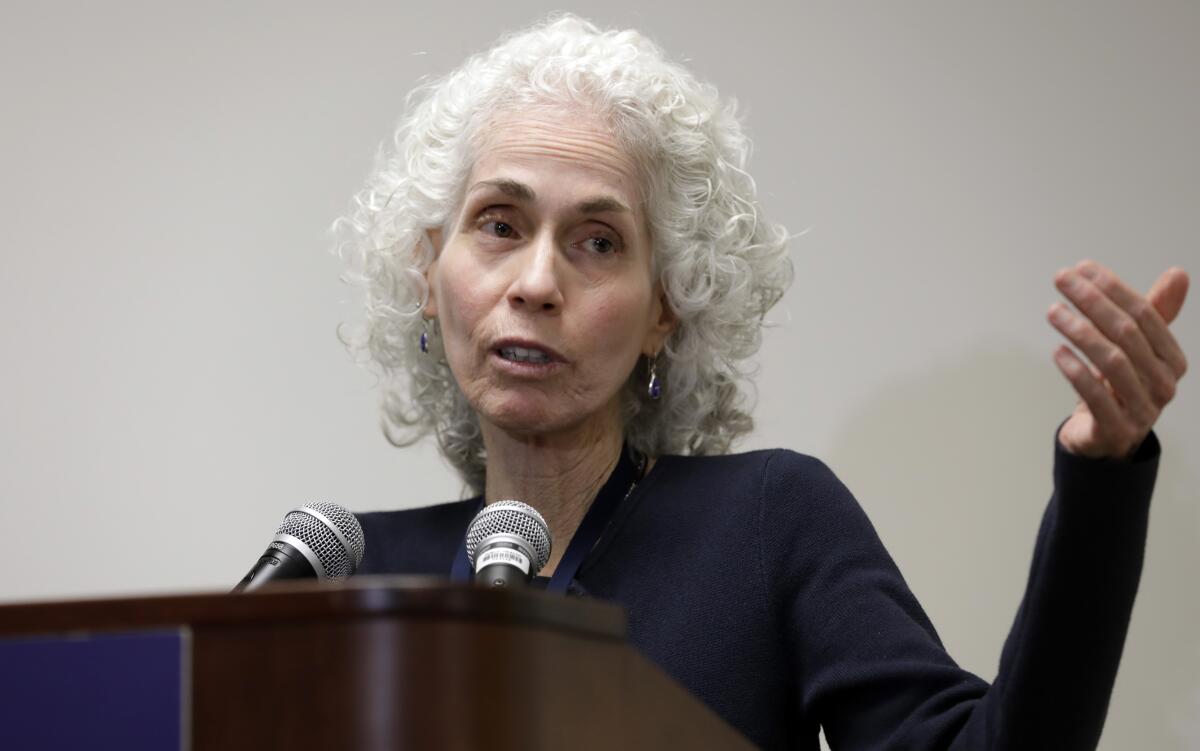 Barbara Ferrer gestures from behind a lectern