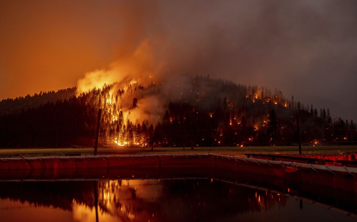 FILE - In this Aug. 21, 2021 file photo long exposure photo, flames from the Dixie Fire spread in Genesee, Calif.  