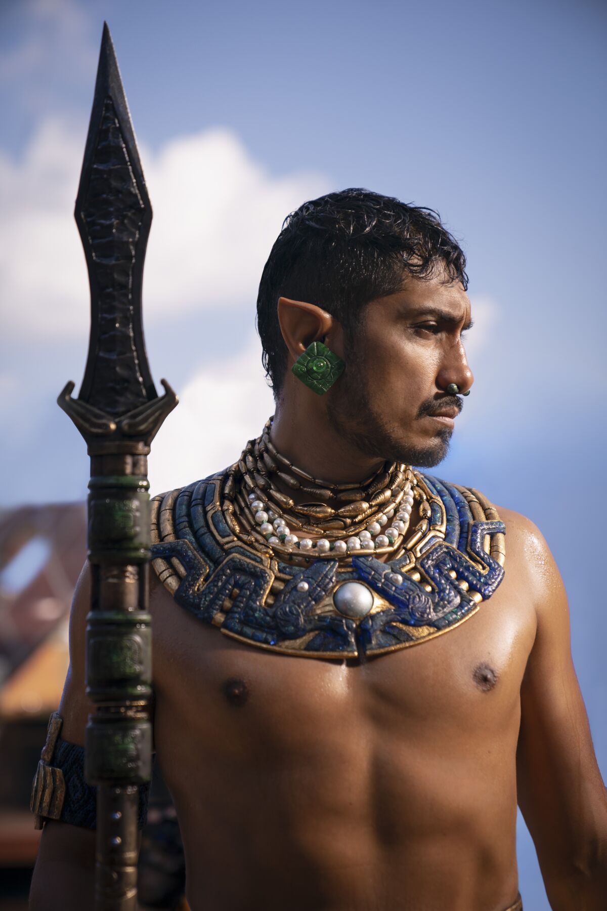 a shirtless man holding a spear