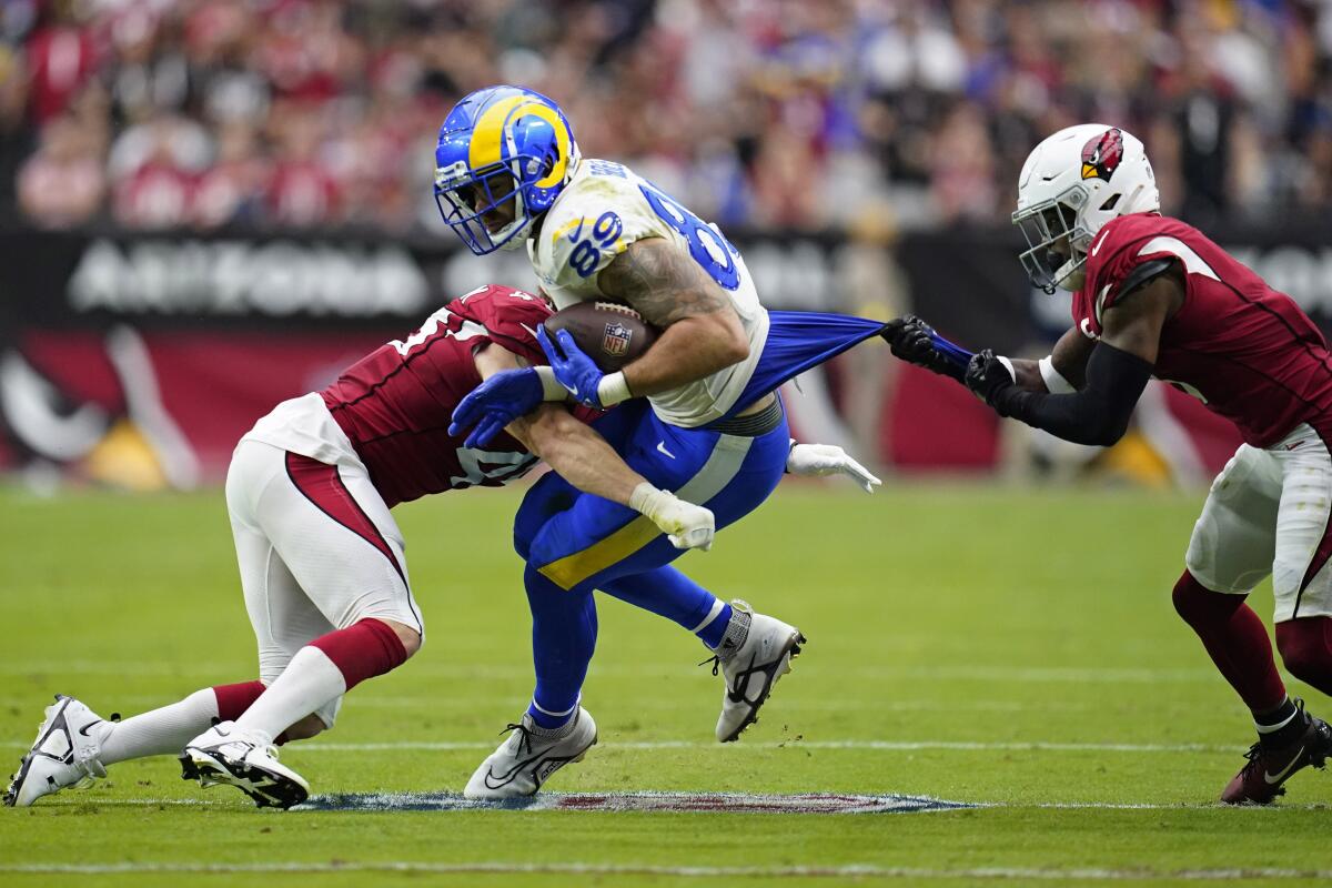 Rams tight end Tyler Higbee is brought down by Arizona's Dennis Gardeck, left, and Budda Baker.