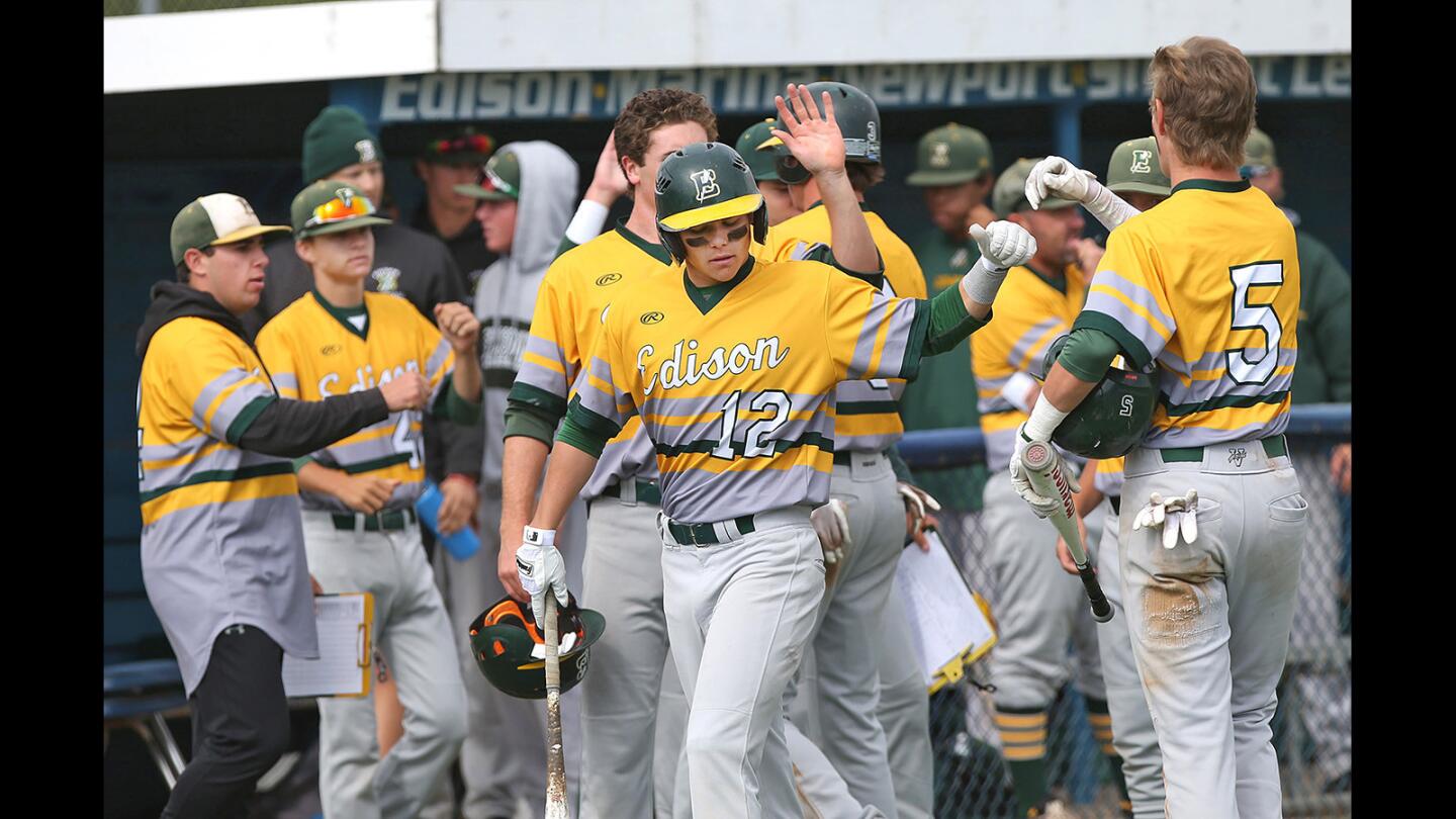 Edison High's Ted Burton (5) high-fives Cole Montgomery after sliding into home safe during boys' baseball against Fountain Valley on Wednesday.