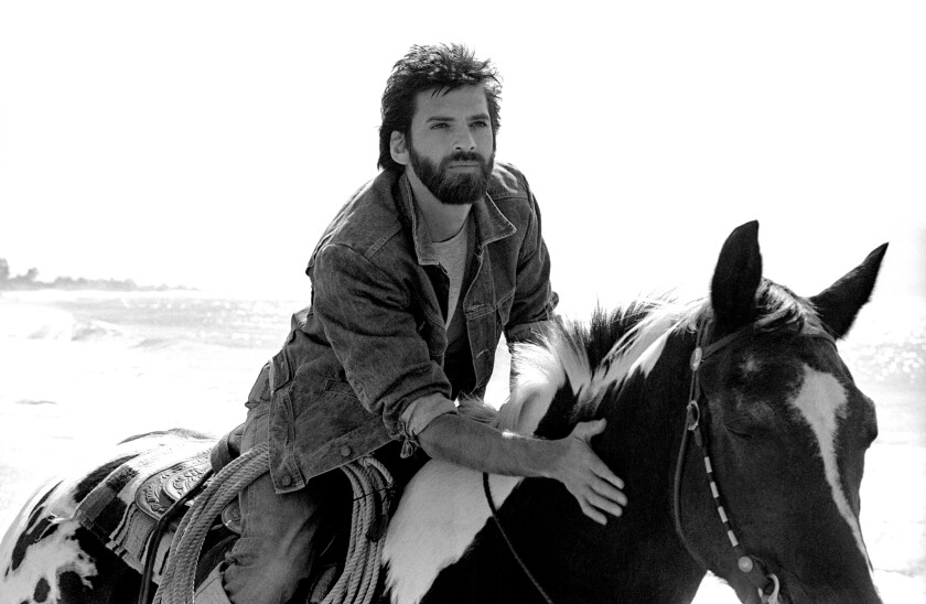 A man rides a horse on the beach.