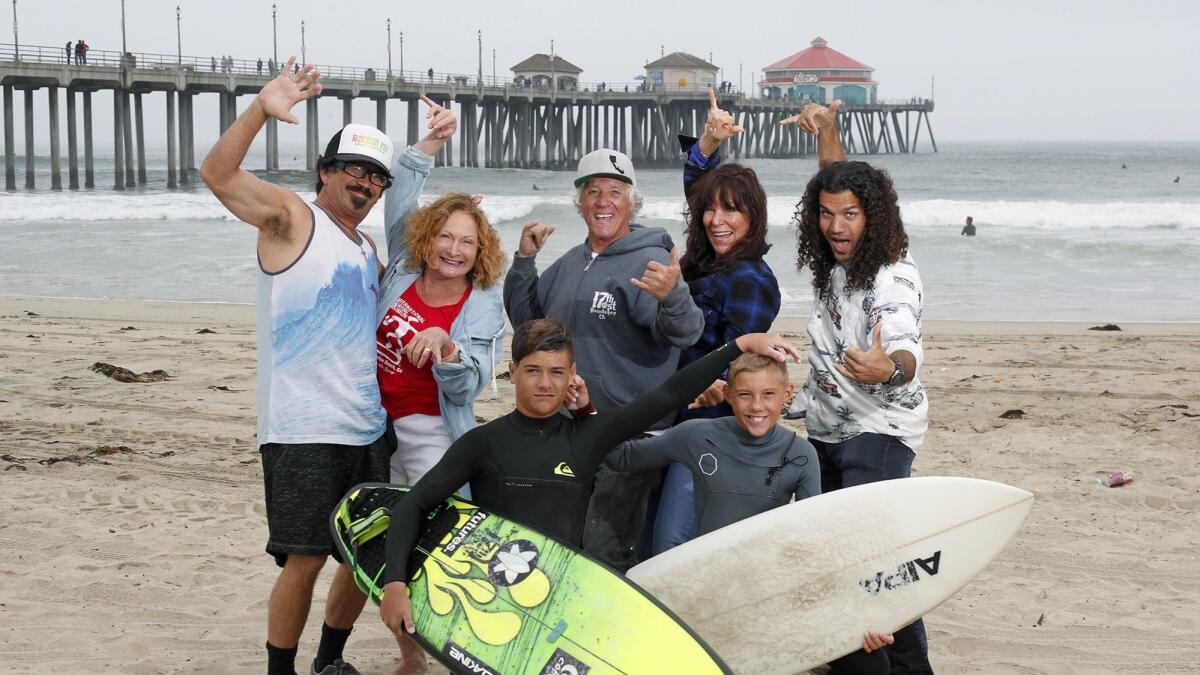 Diana Dehm, second from right in the back row, poses with, back row from left, Rick "Rockin' Fig" Fignetti, Jericho Poppler, Don Ramsey, Eric VanDruff and, front row from left, Kolby Aipa and Parker Wood in Huntington Beach. Dehm envisioned the Surfing Circle of Honor in 2017.