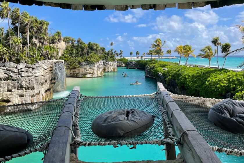 Pillows rest on netted seats where guests can perch above a blue river at the Hotel Xcaret Arte.