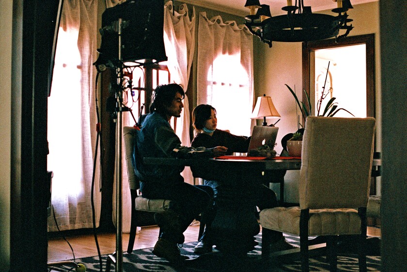 Two people sit at a table on a film set