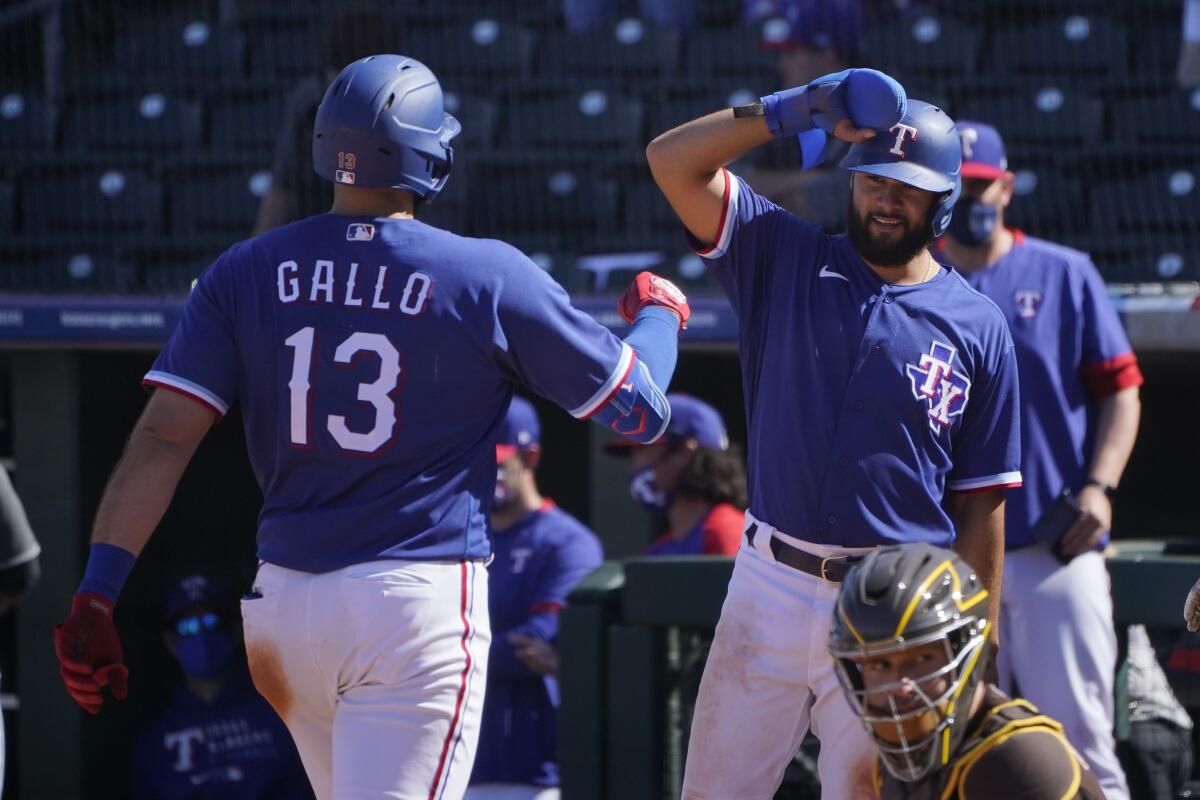 The Rangers' Joey Gallo (13) is greeted at home plate by teammate Isiah Kiner-Falefa