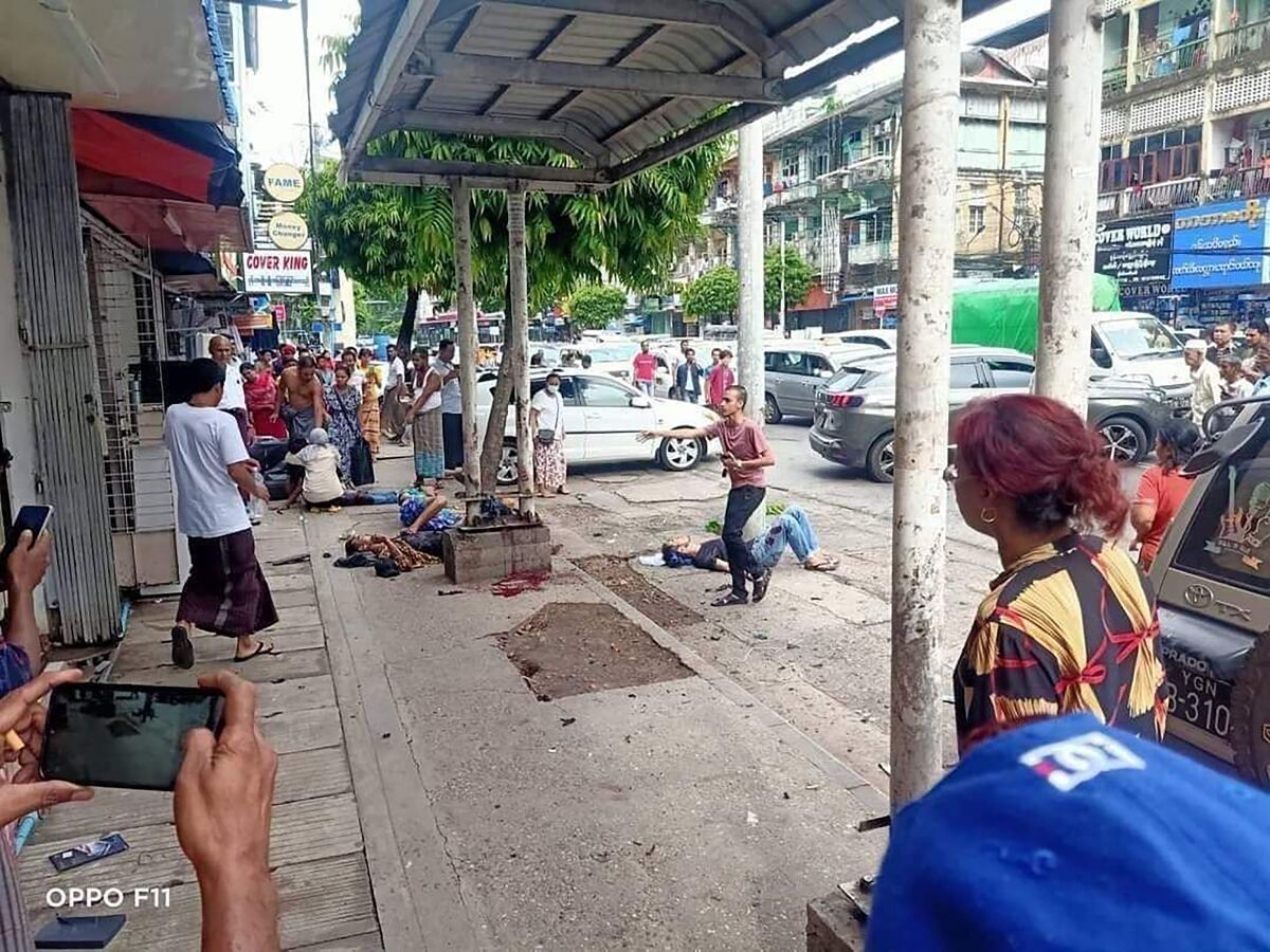 In this photo provided by the information office of Myanmar's military, four injured people can be seen lying on the pavement after an explosion at a bus stop in downtown Yangon on May 31, 2022. One person was killed and nine wounded when what authorities described as a handmade bomb exploded. The military and its foes blamed each other for the blast. (Myanmar Military True News Information Team via AP)