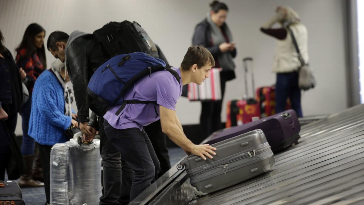 A traveler gathers his luggage at the San Francisco International Airport. Alaska Airlines announced it will raise bag fees, starting Dec. 5.