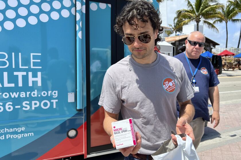Huston Ochoa, a clinical counselor for The Spot, hands out samples of Narcan, which can reduce opioid overdoses, to spring breakers on Fort Lauderdale Beach, Fla., on March 31, 2022. Community activists are warning spring breakers of a surge in recreational drugs being laced with the dangerous opioid fentanyl, and offered them an antidote for overdoses _ which have risen nationally during the COVID-19 pandemic. (AP Photo/Freida Frisaro)