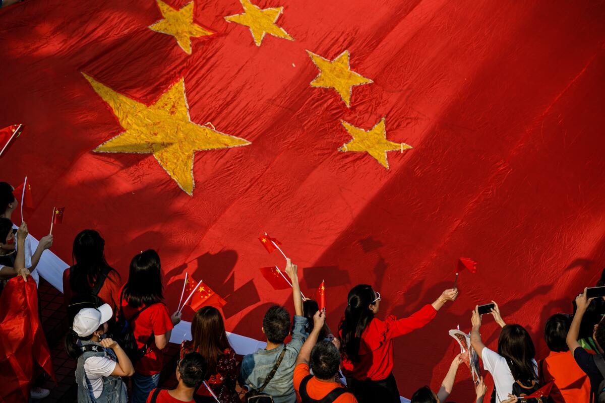 A few dozen people unfurl a large Chinese flag as they gather on the waterfront in Hong Kong on Oct. 1, 2019,  to mark China's National Day.
