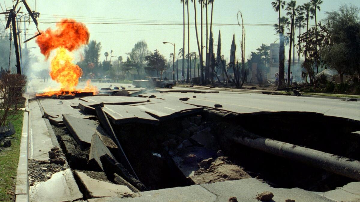 Ruptured gas mains burn behind a giant crater in the 11600 block of Balboa Boulevard in Granada Hills on Jan. 17, 1994, after the Northridge earthquake. Several homes burned near where the gas line exploded.