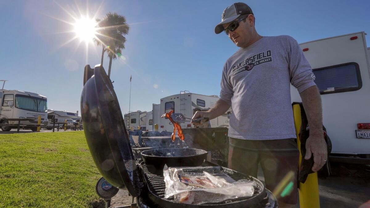 Steve Robinson, who came with his family from Bakersfield to camp at Dockweiler RV Park, prepares breakfast in the warm holiday weather.