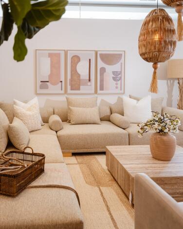 A cream colored sectional is featured alongside artwork and pillows at the Pampa Furniture showroom.