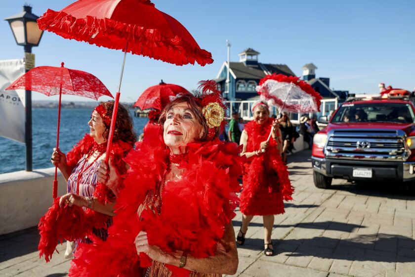 Victoria Rosas and other members of The San Diego Parasol Strutters march along the boardwalk at Seaport Village.