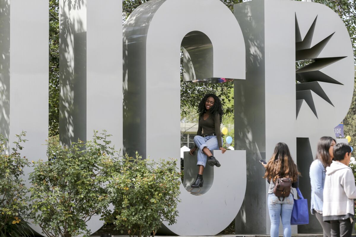 Tiffany Isichei, 18, sitting, gets her photo taken at one of the most photographed spots on the UC Riverside campus on Highlander Day.
