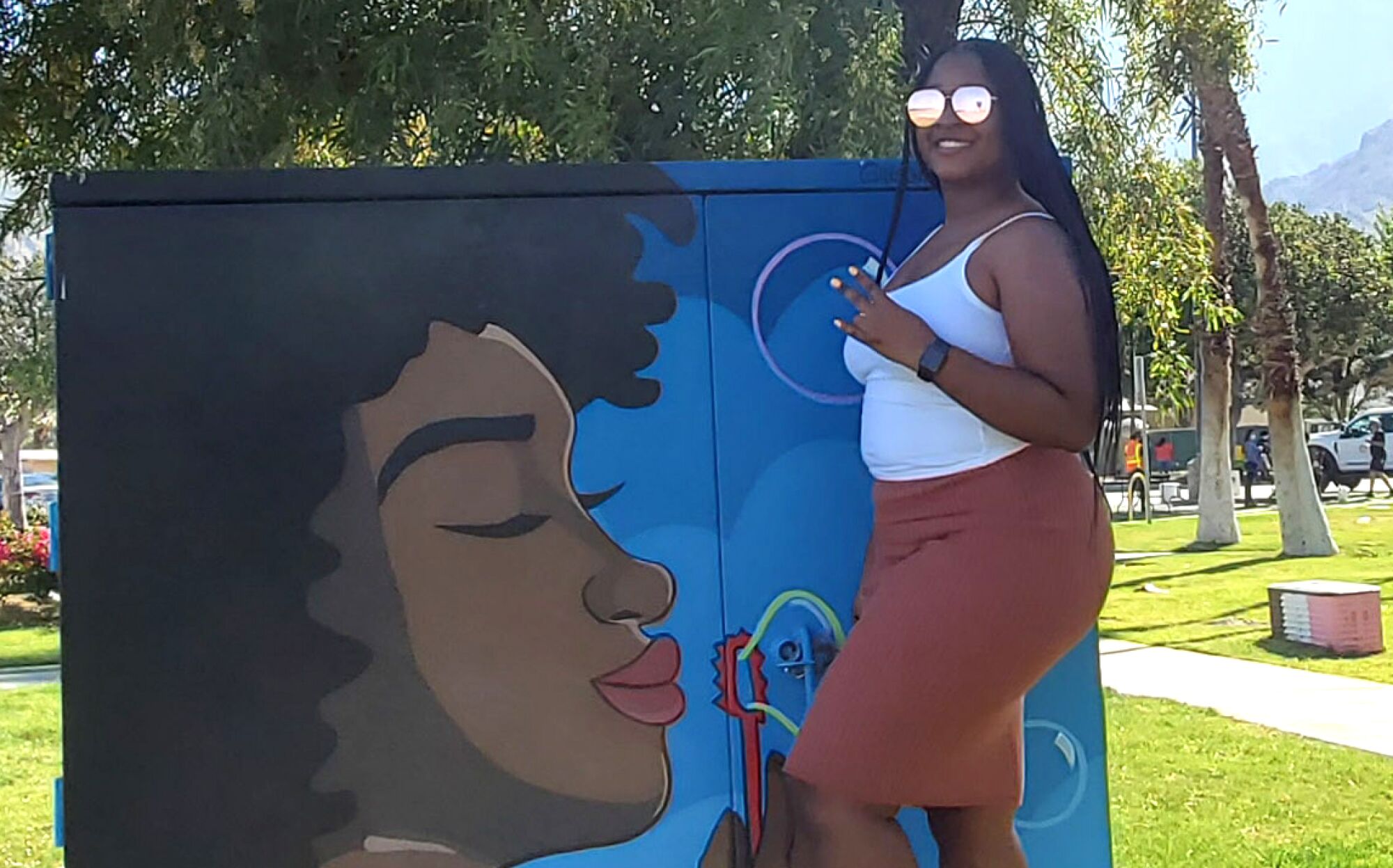 Palm Springs native La’Ronjanae Curtis stands by a mural of a person blowing bubbles.