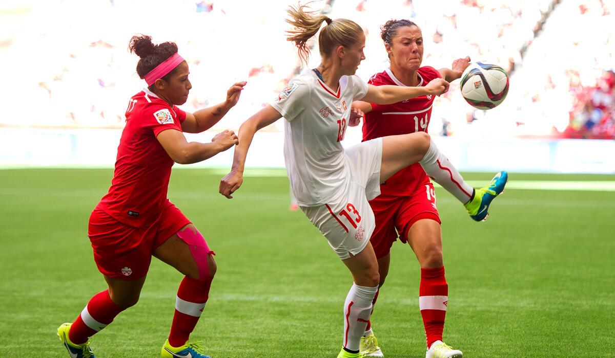 Switzerland's Ana-Maria Crnogorcevic, center, tries to control the ball while being challenged by Canada's Josee Belanger, left, and Melissa Tancredi during the FIFA Women's World Cup match on Sunday.
