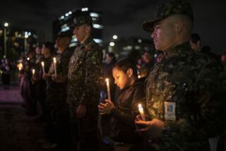 Un niño sostiene una vela durante una vigilia en honor de soldados muertos en un ataque reciente por parte de disidentes de las FARC, en el Monumento a los Héroes Caídos, el viernes 9 de diciembre de 2022, en Bogotá, Colombia. (AP Foto/Iván Valencia)
