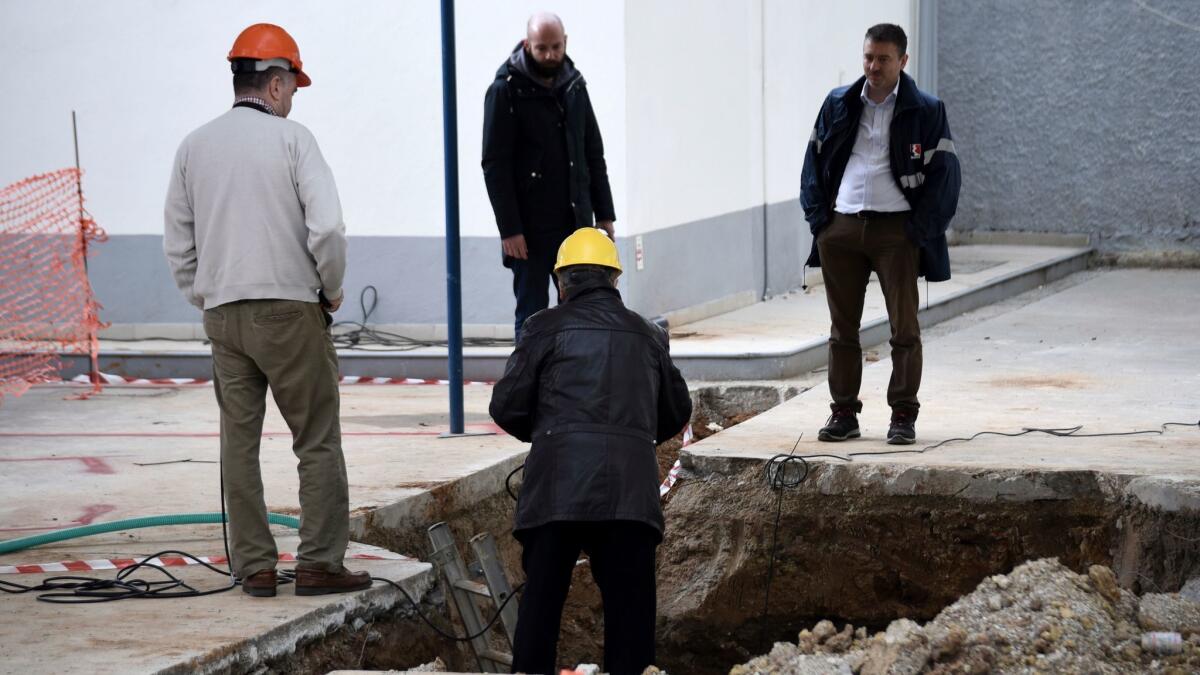 Experts check the location where an unexploded World War II bomb was found beneath a gas station in Thessaloniki, Greece, on Feb. 9.