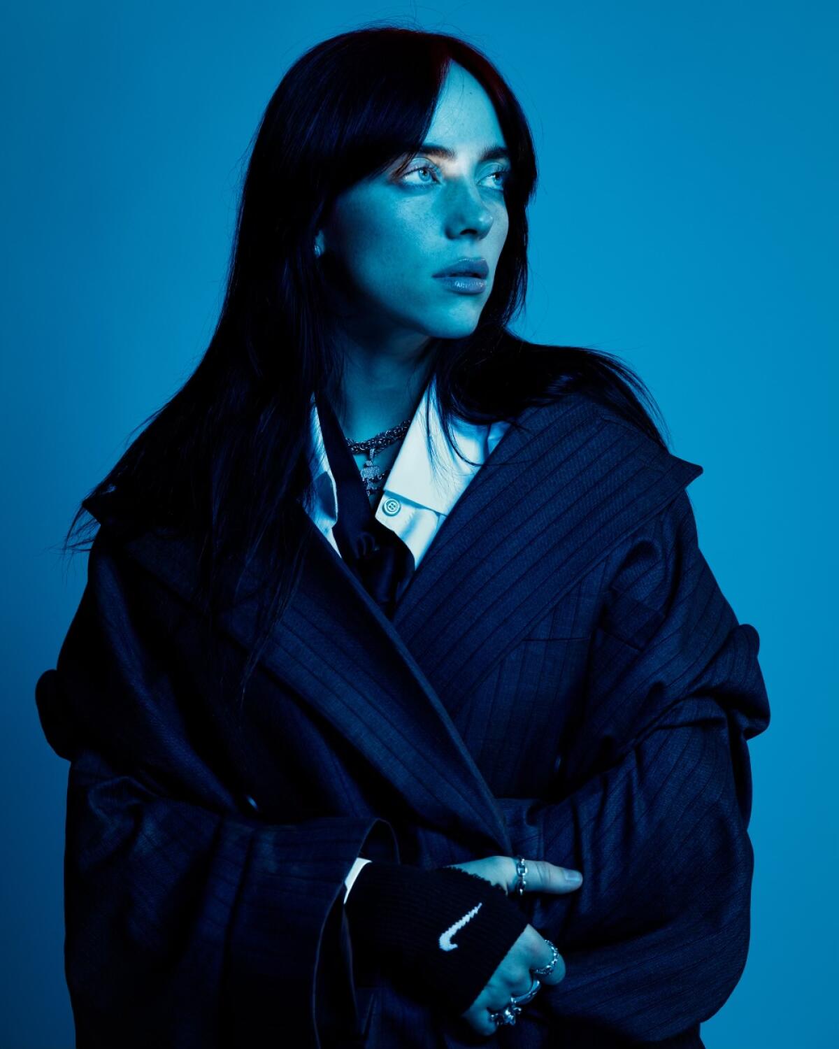 A woman with dark hair looks to her left in a cyan-tinted photo