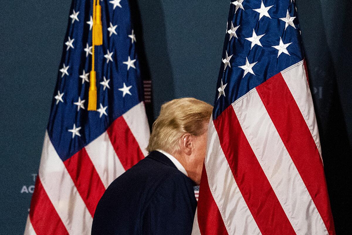The back of President Trump's head between two American flags
