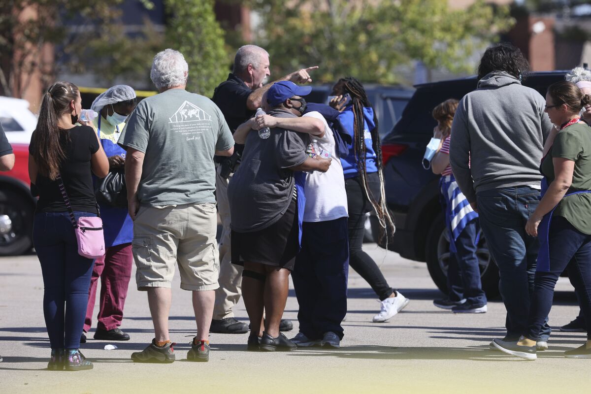 People embrace as police respond to the scene of a shooting 