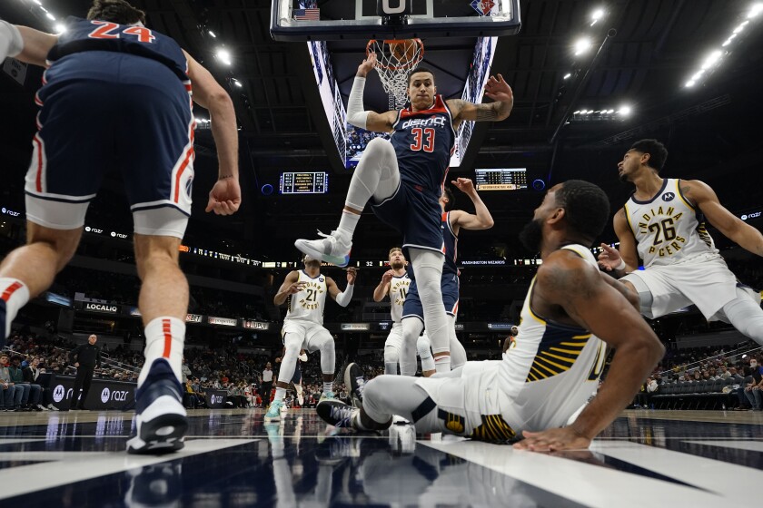 Washington Wizards forward Kyle Kuzma (33) comes down after failing to block a shot by Indiana Pacers guard Brad Wanamaker, bottom right foreground, during the first half of an NBA basketball game in Indianapolis, Monday, Dec. 6, 2021. (AP Photo/AJ Mast)