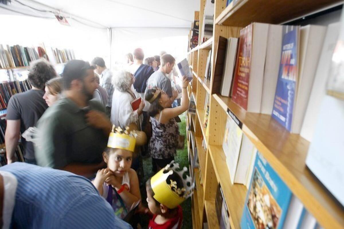 Visitors look over books to purchase at the $5 or Less Book Store tent at the Los Angeles Times Festival of Books at USC on April 22, 2012.