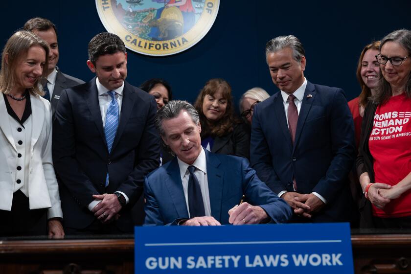 Flanked by lawmakers and gun safety advocates, Gov. Gavin Newsom signs new gun legislation into law at the Capitol Annex Swing Space in Sacramento on Sept. 26, 2023.