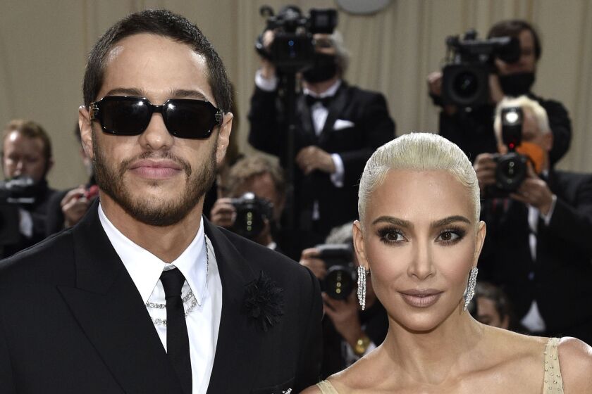 A man in sunglasses and a woman with platinum hair arrive at a gala together