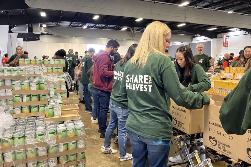 Employees of Newport Beach-based company PIMCO pack some 15,000 boxes Saturday with food and goods for families in need.