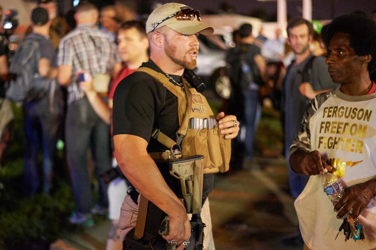A member of the Oath Keepers walks with his weapon on the street during protests in 2015 in Ferguson, Mo.