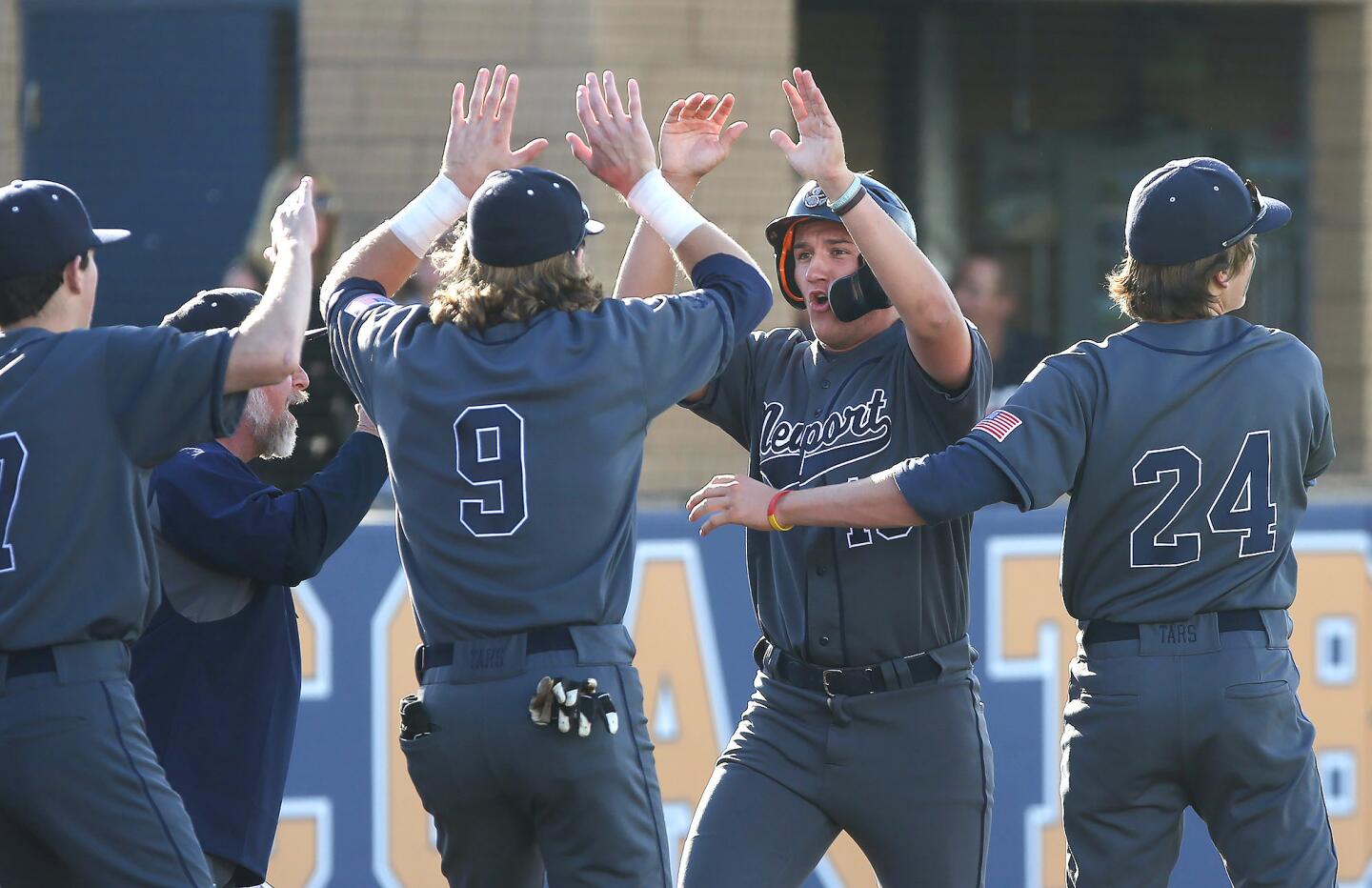 Newport Harbor High's Kelly Austin, middle, celebrates another run with teammates John Olmstead (9) and Braham Duncan (24) during the Battle of the Bay game against Corona del Mar at Orange Coast College on Wednesday.